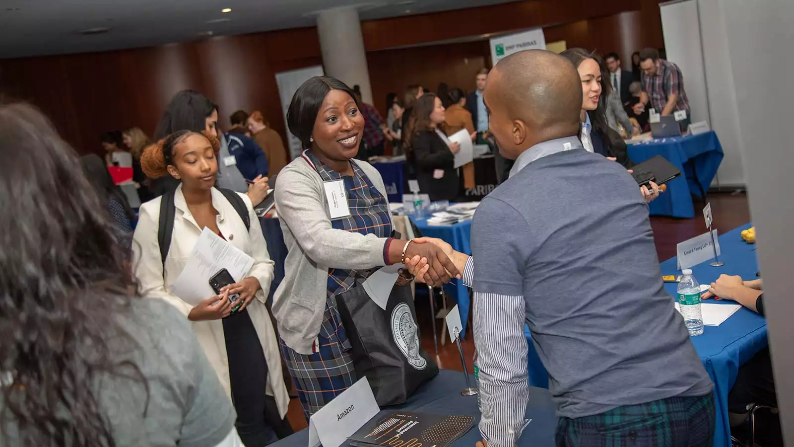 Black woman shakes hands with an employer at a busy networking event