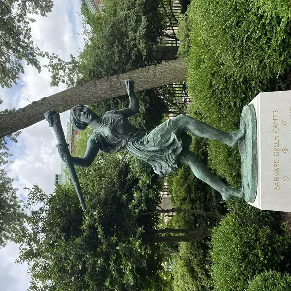 Head on shot of Greek Games statue and base with greenery in the background