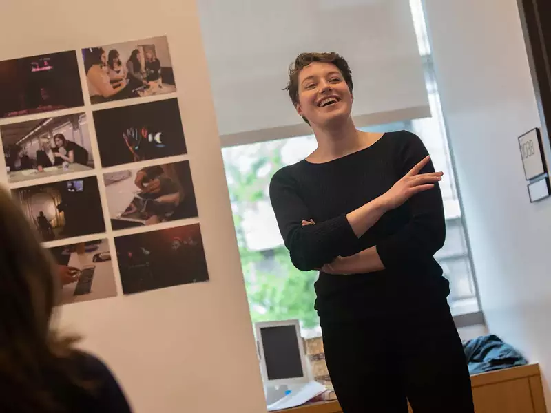 Young woman standing in an office, laughing