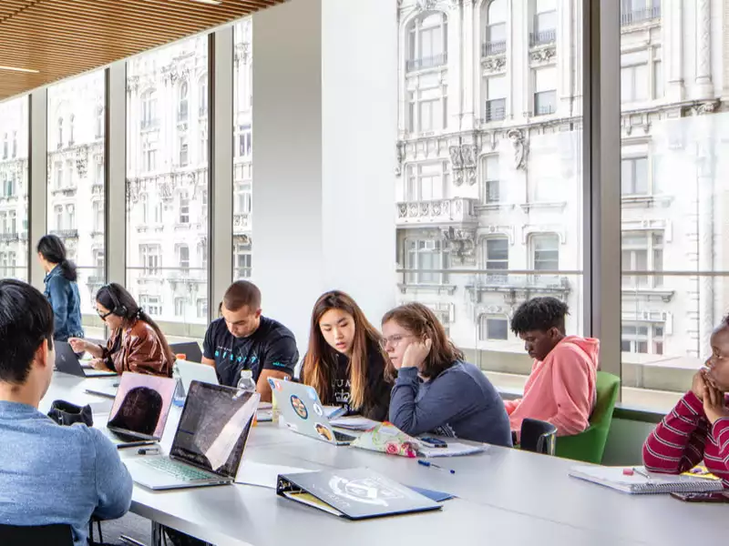 several students around a large conference table with large windows on one side